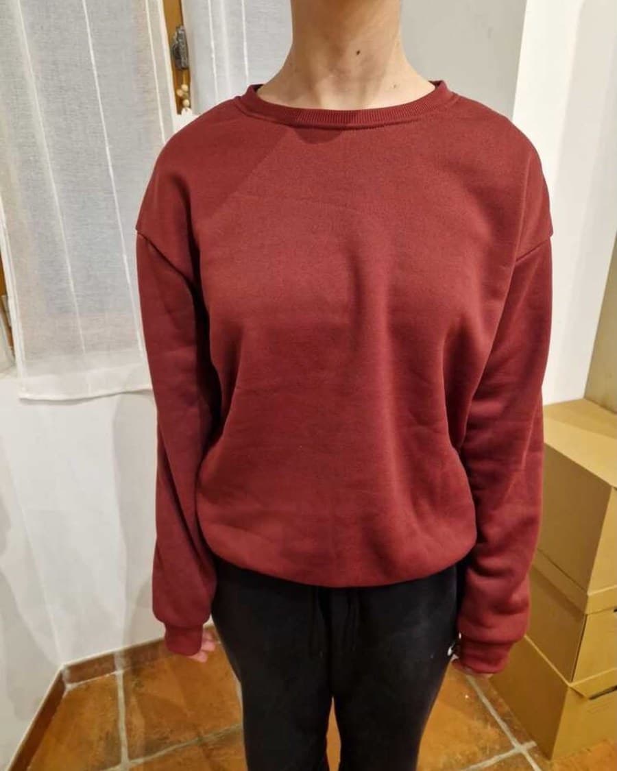 Le maillot sur un cintre, face visible : col et bandes rouges, croix dorée côté cœur.